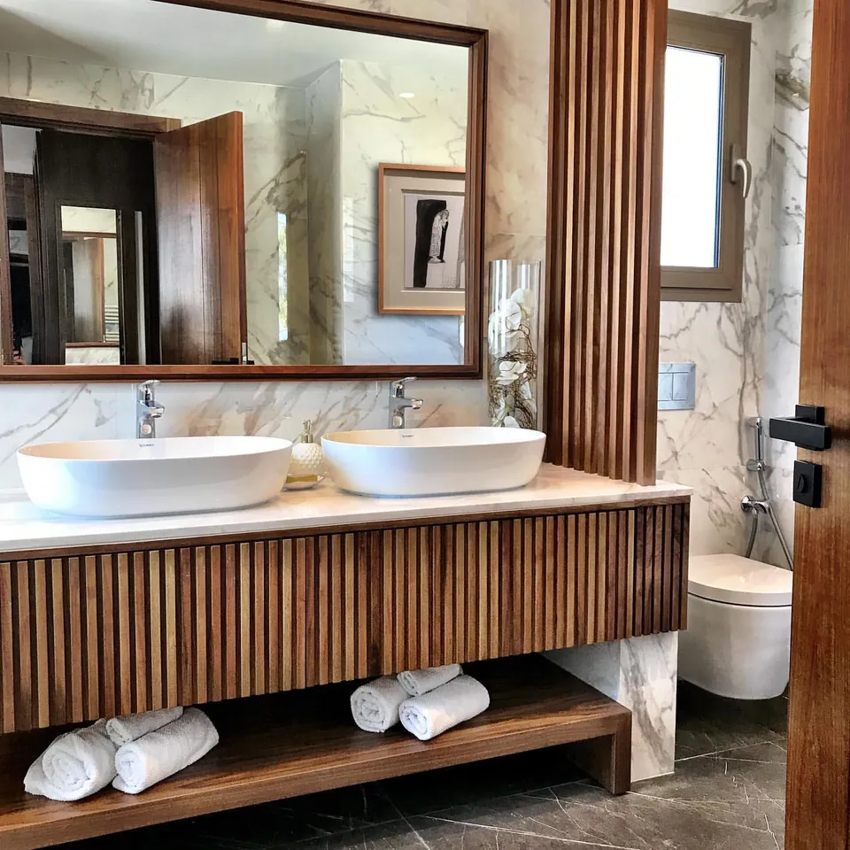 Salle de bains : double vasque blanche, meuble à lames de noyer, marbre Calacatta