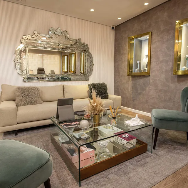 Showroom 2023 : canapé clair, fauteuils verts, niches encadrées de laiton sur un mur taupe