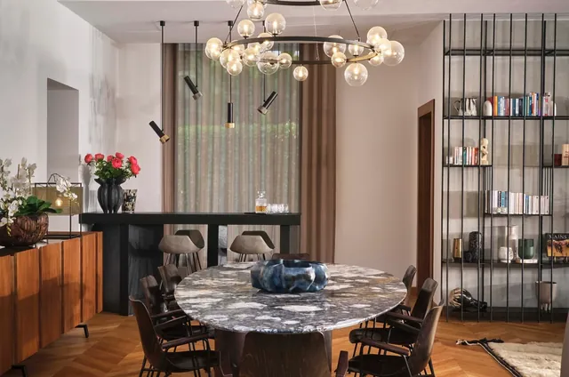 Salle à manger : table ronde en marbre, suspension à globes, bibliothèque noire