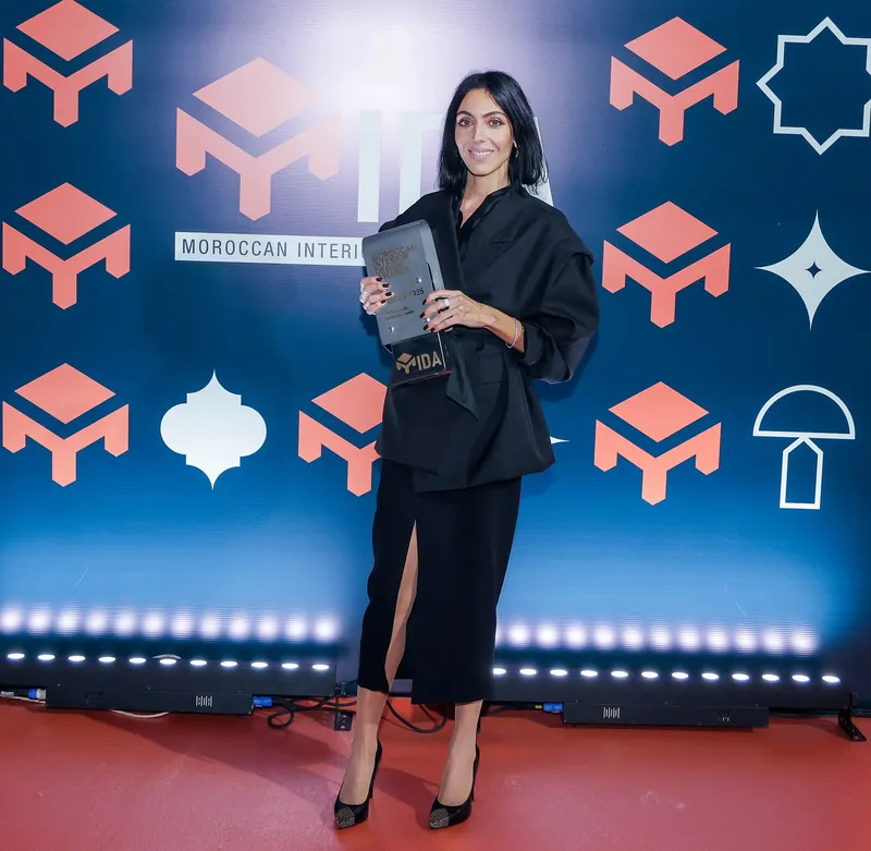 Meryem Tazi tenant le trophée devant le mur des Moroccan Interior Design Awards