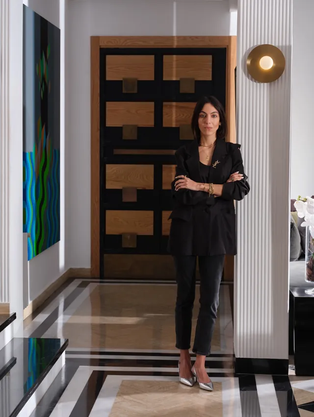 Meryem Tazi dans l’entrée de la maison, devant la porte en bois