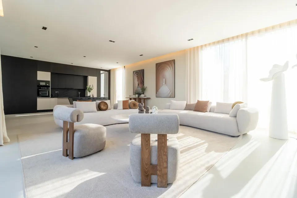 Séjour baigné de lumière : canapé courbe blanc, tables basses rondes, grandes baies sur le jardin