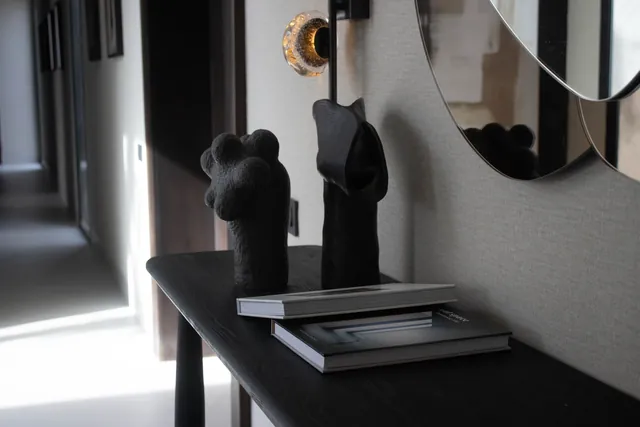 Console noire, sculptures et miroir rond